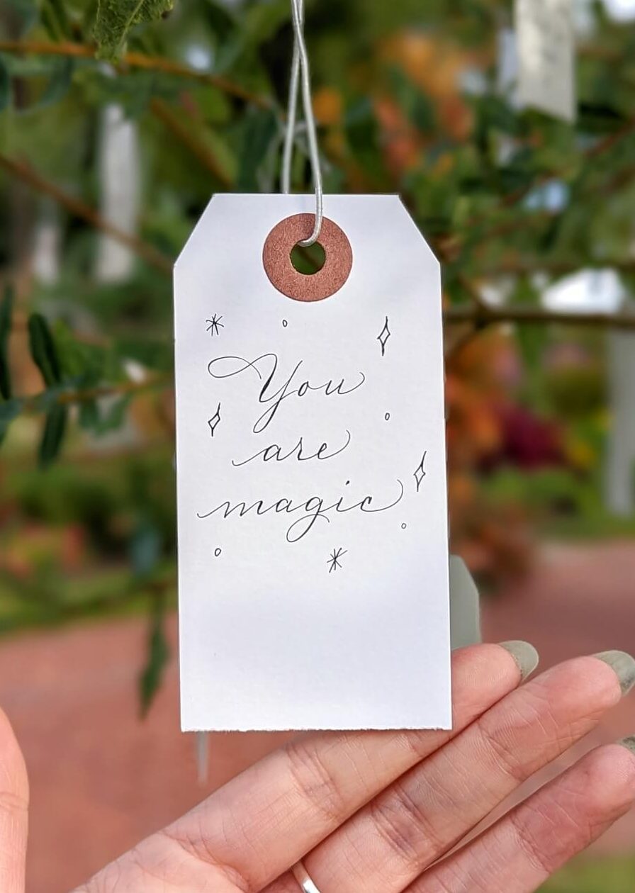 paper tag hanging from wishing tree with "You are magic" written on it in calligraphy